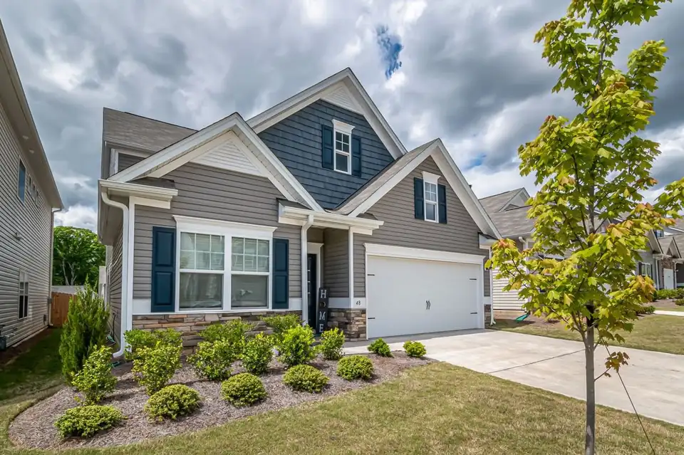 Two-story gray and blue home with gutters along the roofline